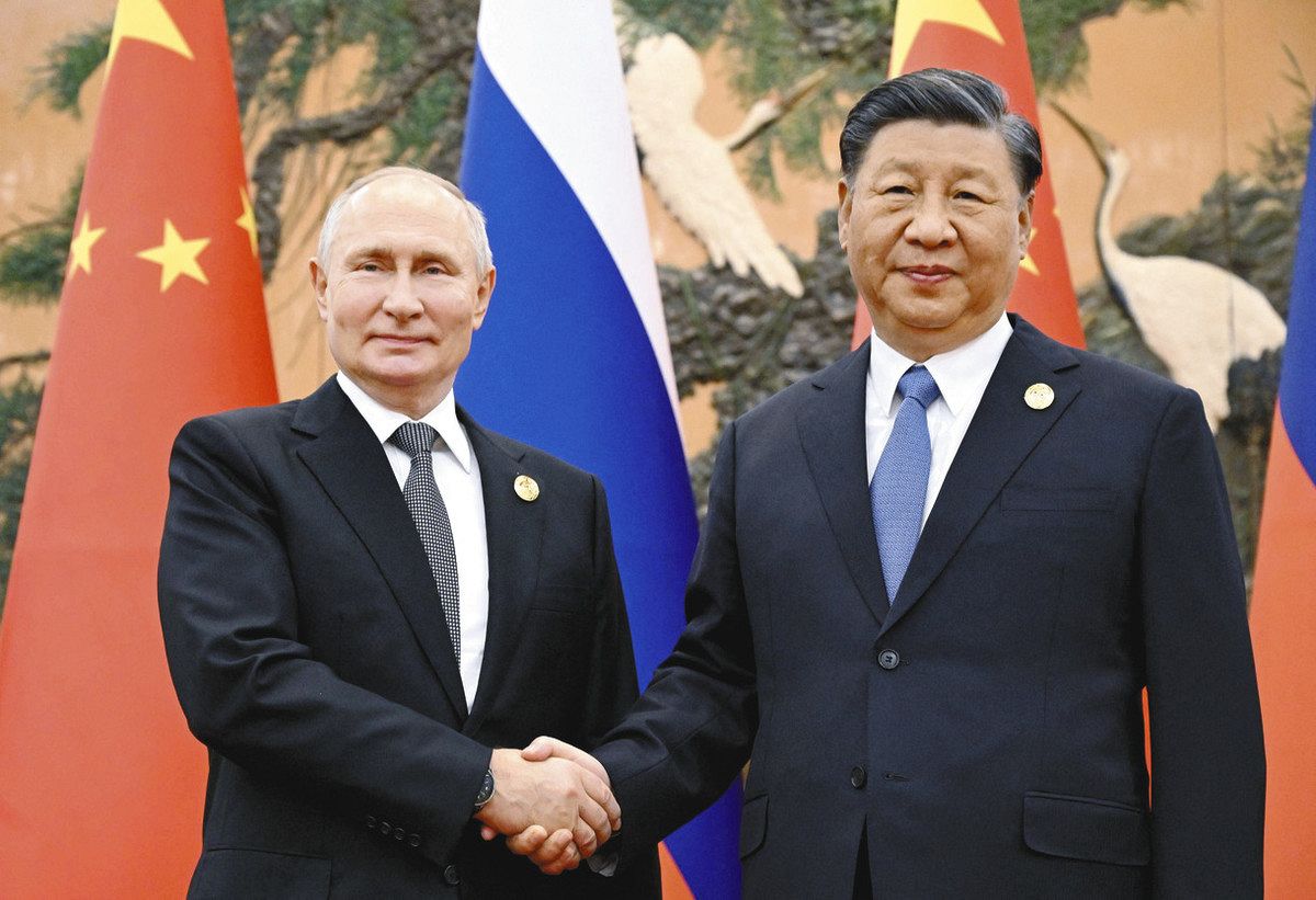 18日、北京で、首脳会談で握手を交わすロシアのプーチン大統領（左）と中国の習近平国家主席＝ロイター・共同
