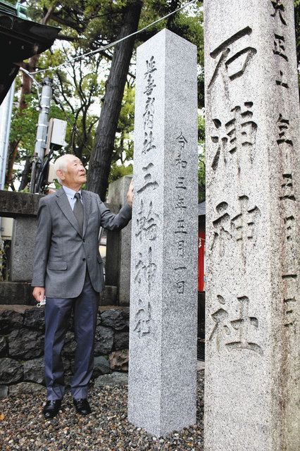 祖父が寄贈した石碑（右）の横に並ぶ、自分が寄贈した石碑を見つめる越田宏さん＝金沢市本多町の石浦神社で
