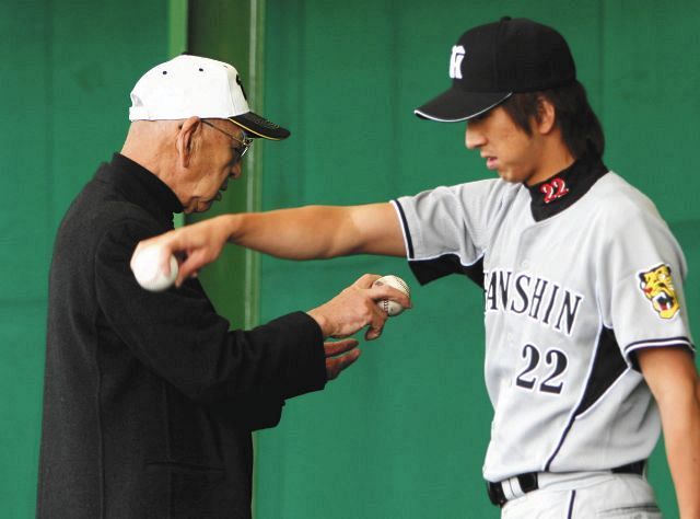 藤川（右）にフォークの握りを教える杉下茂氏＝2008年2月7日、沖縄・宜野座球場で