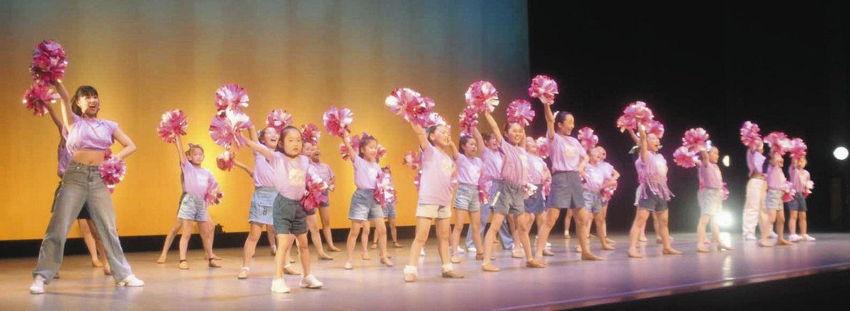チアドリームプロジェクトのメンバー（左）に指導を受け、チアダンスを披露する子どもたち＝福井市の県民ホールで
