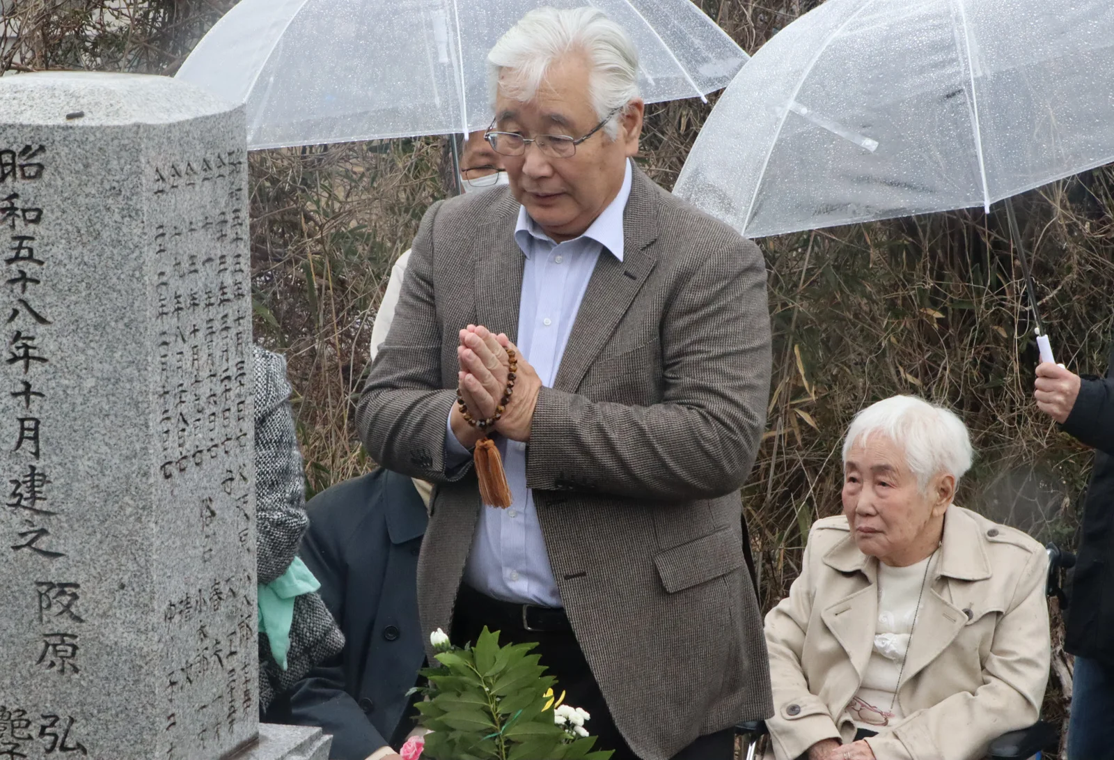 再審開始決定を弘さんの墓前で報告した弘次さんとつや子さん