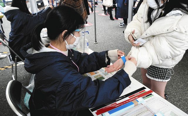 ワクチン接種かＰＣＲ検査陰性の証明が確認できた観客にリストバンドを着けるスタッフら＝名古屋市南区の日本ガイシホールで
