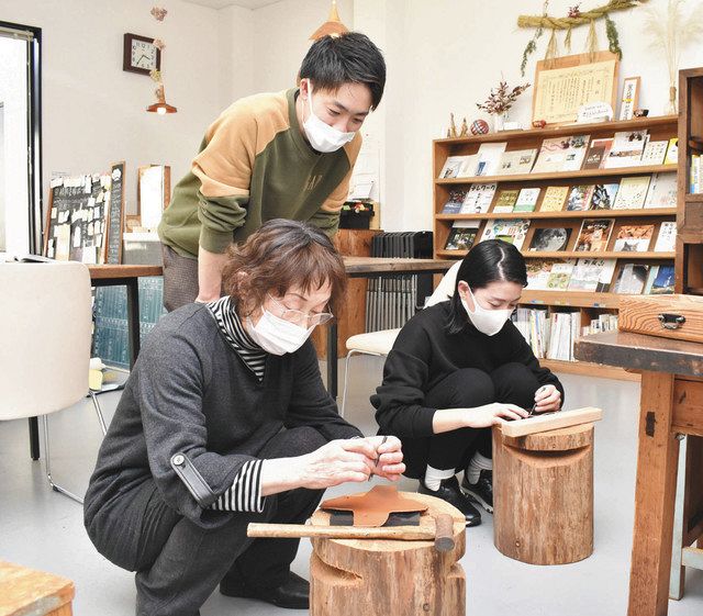 田口さん（奥）の指導を受けながら革小物を作る受講者＝木曽町のふらっと木曽で