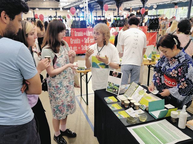 パリのイベントで、来場者にいく里茶の説明をする会のメンバー（右）＝いく里の会提供