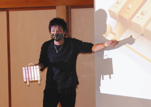 木のおもちゃを手に、おもちゃ美術館について説明する星野さん＝木曽町新開の「ふるさと体験館きそふくしま」で 