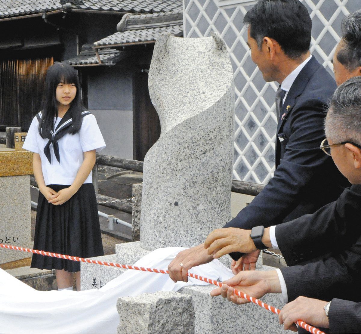 石彫を除幕する田口さん（左）＝中津川市本町で

