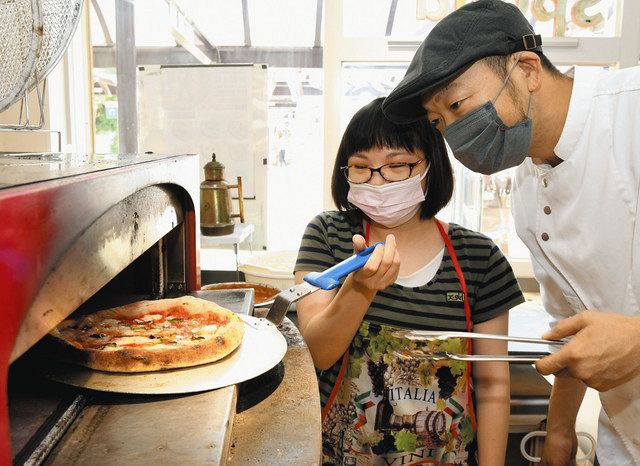 白木さん(右)と一緒に、焼き上がったピザを窯から出す参加者ら=瑞穂市別府のSPADA穂積店で