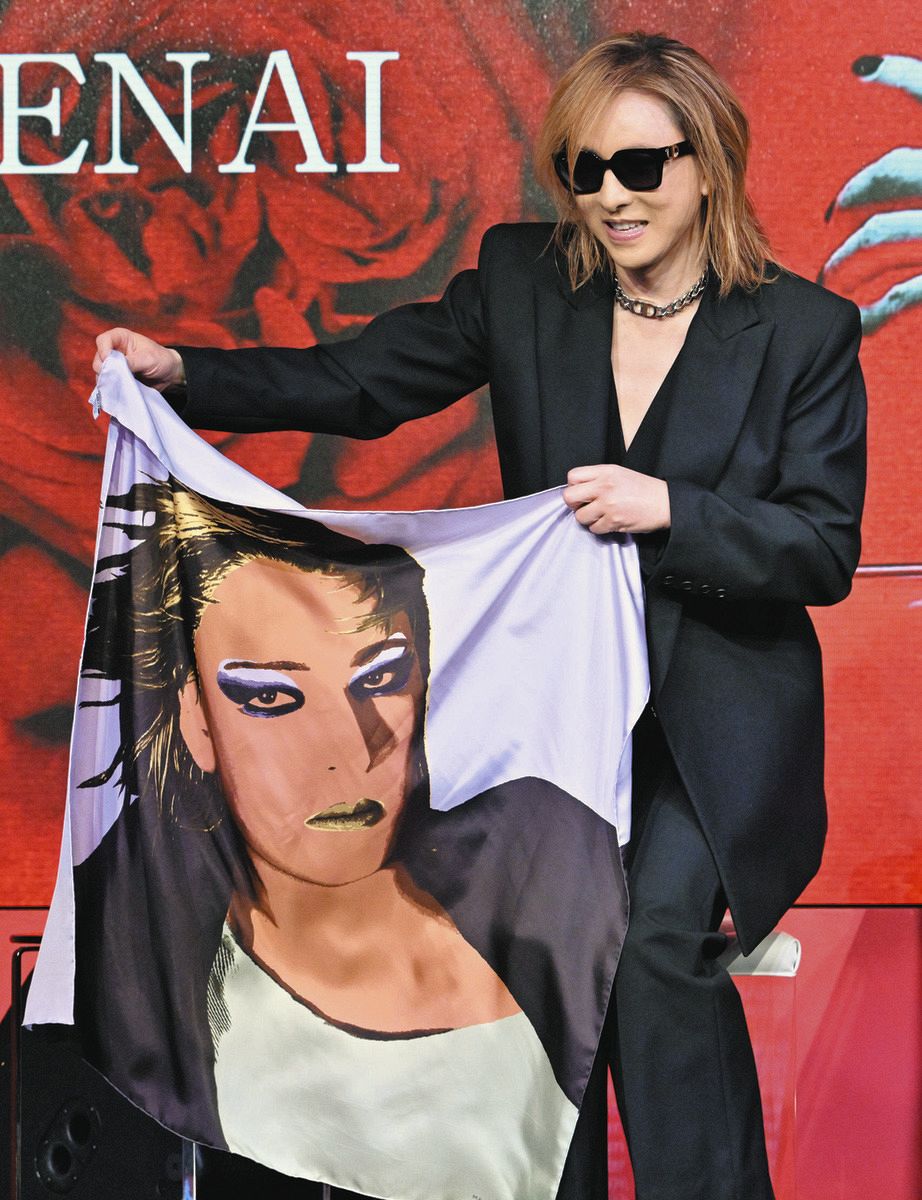 記者会見でオリジナルスカーフを手にする