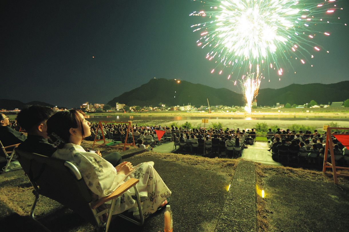夜空を彩る大輪の花火を楽しむ来場者たち。奥は金華山=岐阜市