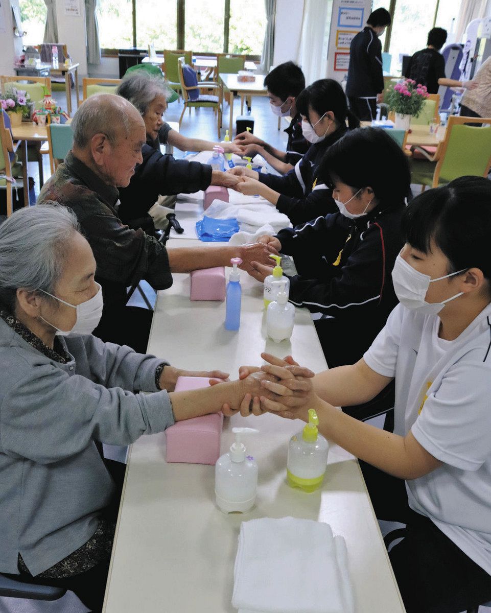 手のマッサージをする生徒（右側）と避難者＝輪島市気勝平町で 