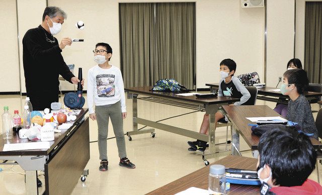 風をさえぎってもボールが浮かぶかどうかを子どもたちと実験で確かめる貝田明さん（左）＝川北町文化センターで 