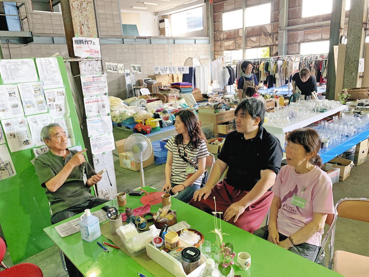 語り合う「みんなの畑の会」の西田敏明さん、被災した人や　ボランティアら。寄せられた生活必需品が並ぶ＝金沢市湊４で 