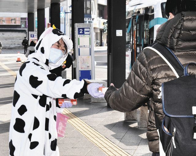牛乳を配りながら消費拡大を呼び掛けるＪＡ職員（左）＝松本市の松本駅前で 