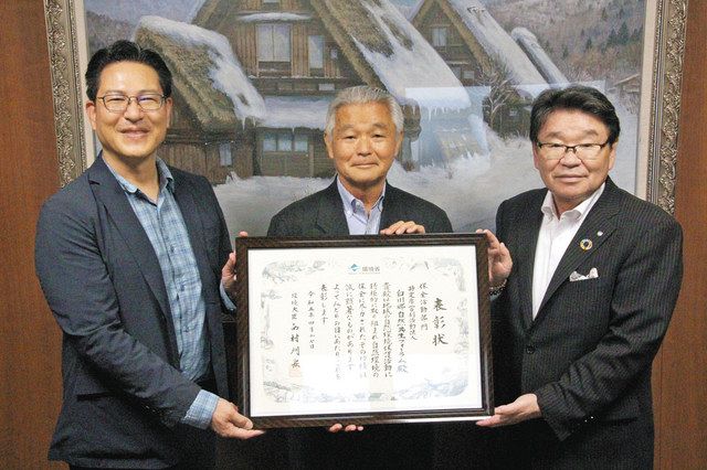 成原村長（右）から表彰状を受け取る田中理事長（中）と山田俊行学校長＝白川村役場で 