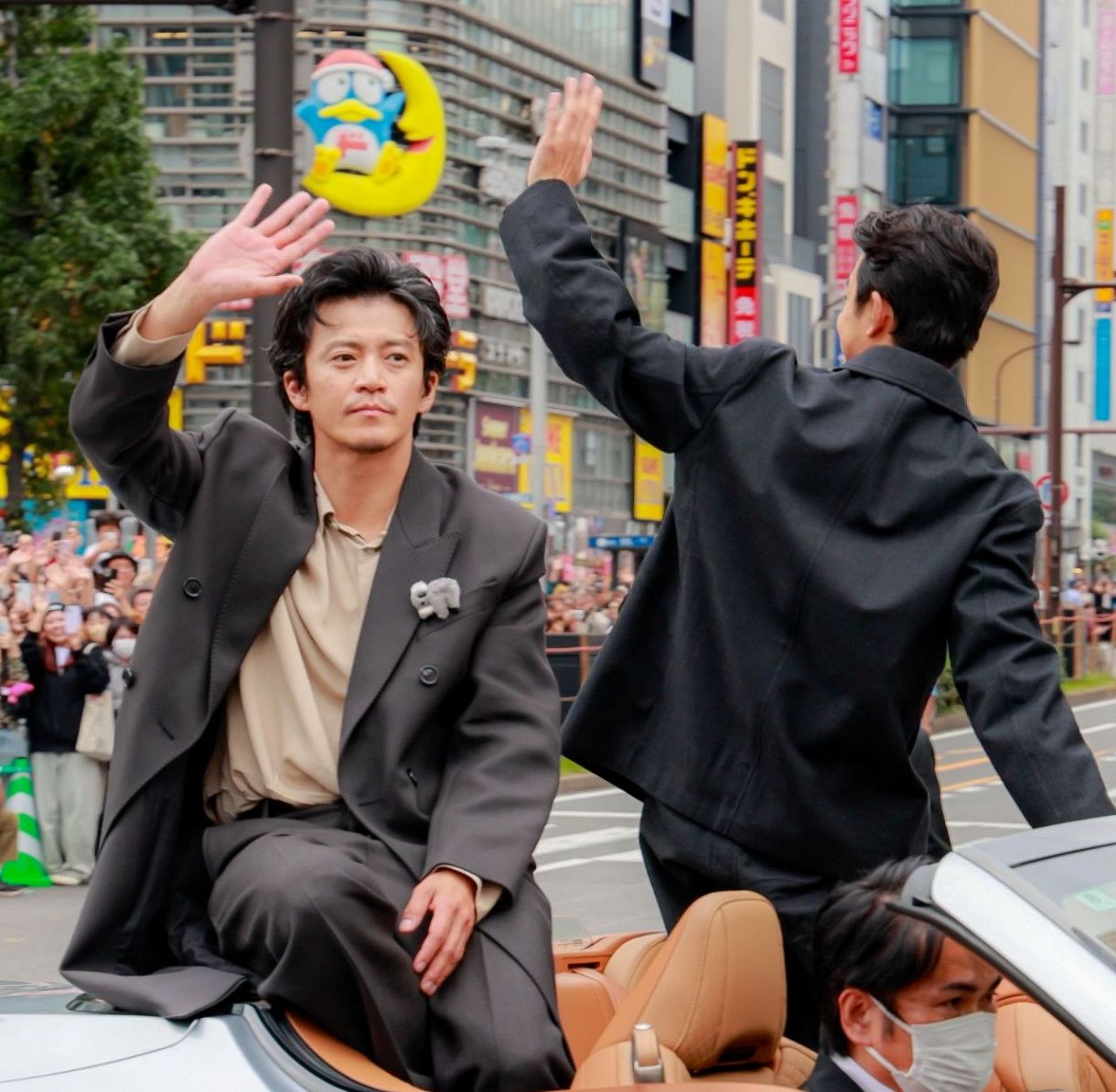 パレードで沿道の人たちに手を振る俳優の小栗旬さん（左）と仲野太賀さん