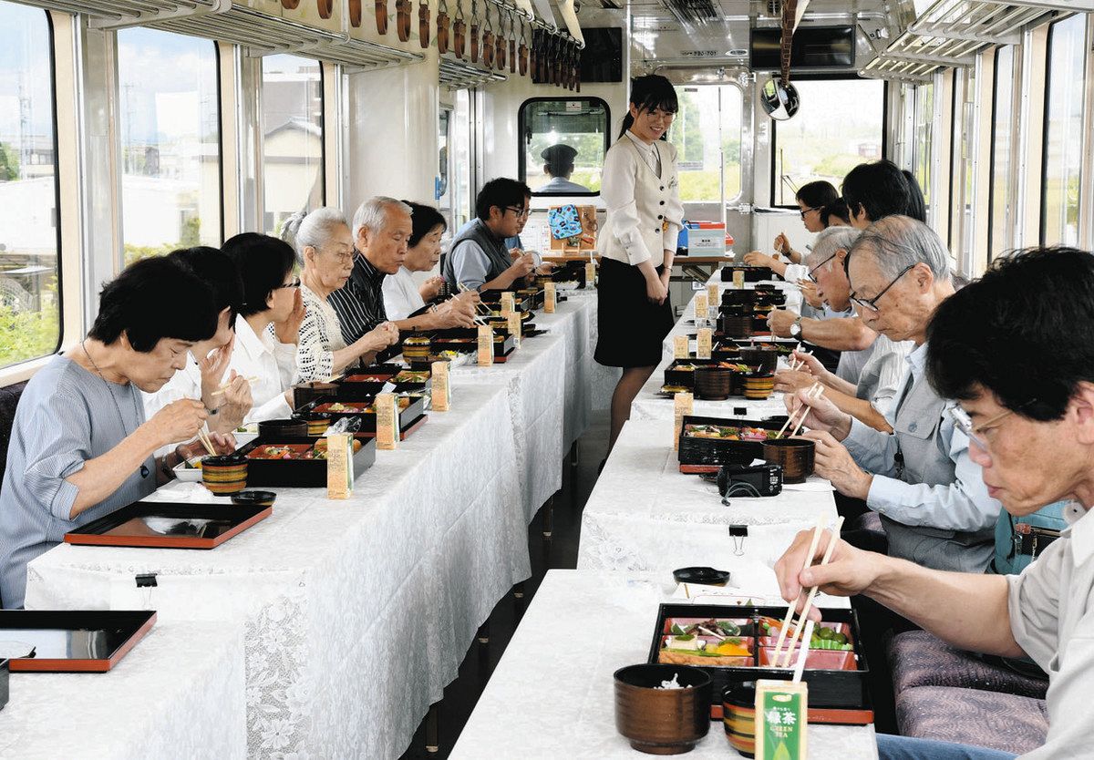 河瀬さん（中央奥）の話を聞きながら、報恩講料理を楽しむ参加者＝樽見鉄道の列車内で 