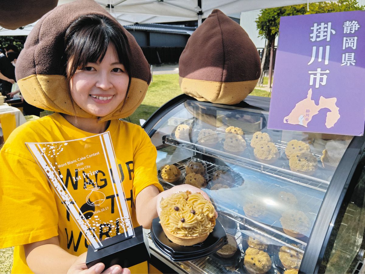 優勝トロフィーと「掛川生まれのチーキーロンロン」を手に笑顔を見せる雪島さん＝恵那市で