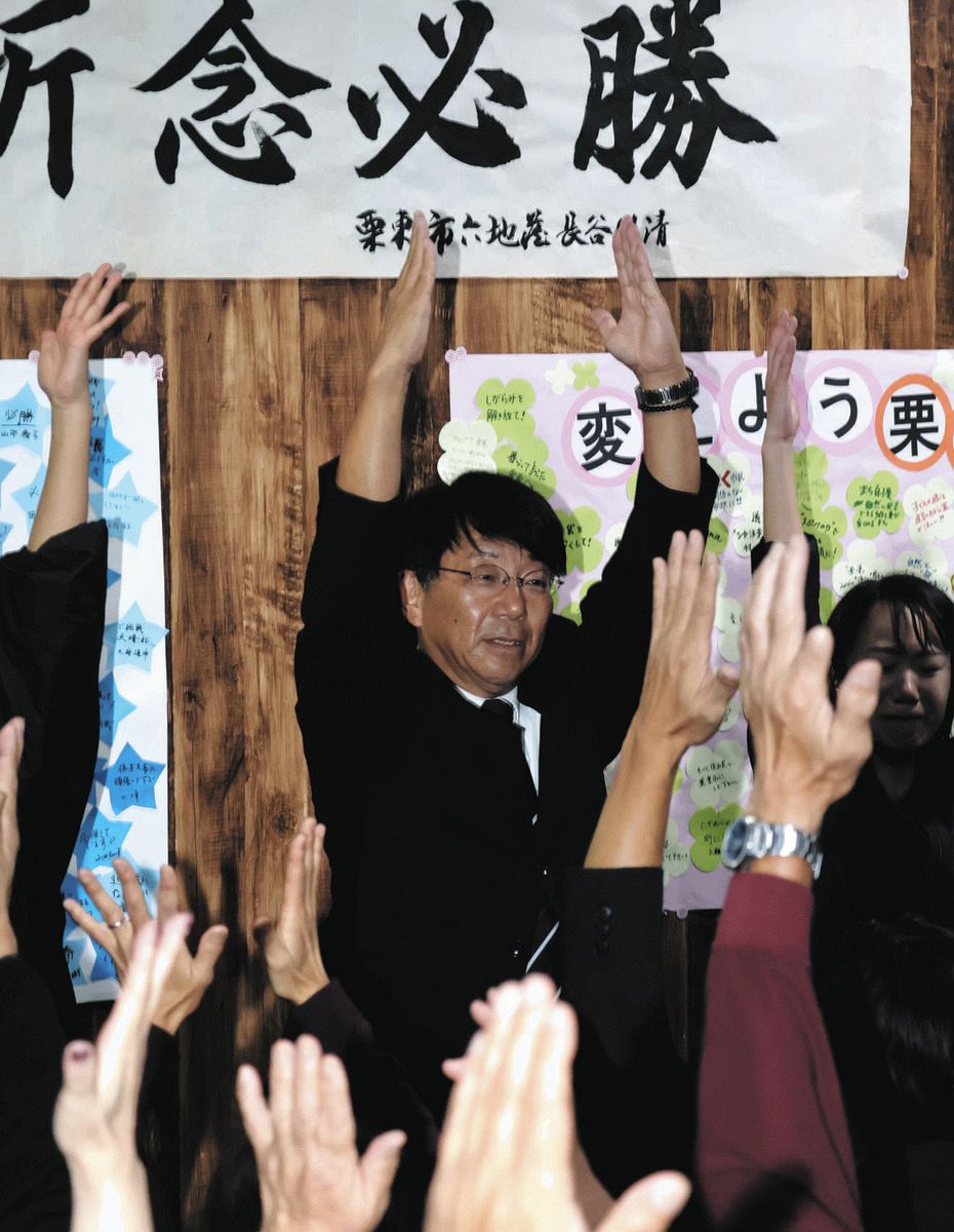 万歳で当選を喜ぶ九里さん＝栗東市安養寺の事務所で