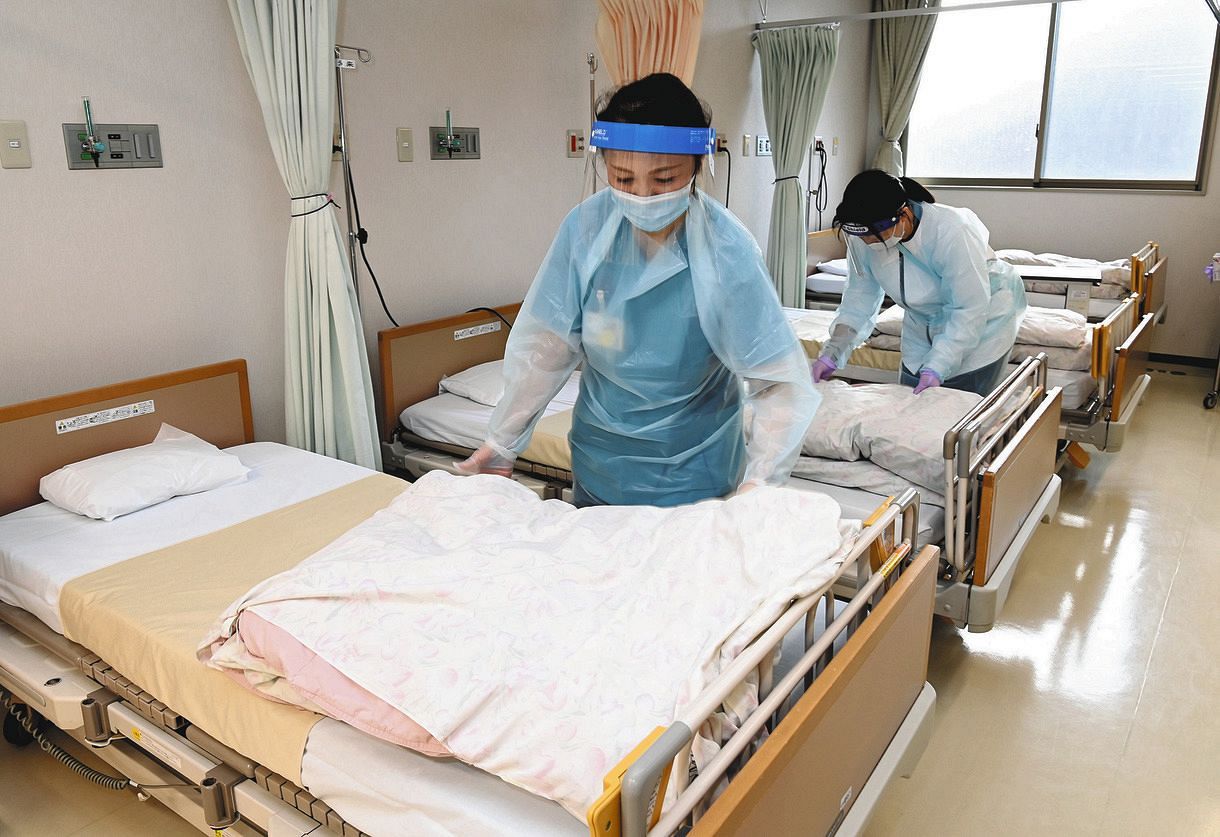 新型コロナウイルス感染を防ぐため外来の処置用ベッドを整える看護師ら