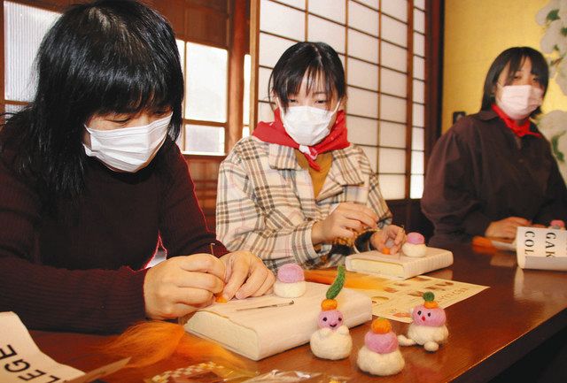 羊毛フェルトで鏡餅を作るひとり親の女性（左）と学生ら＝金沢市片町の金沢学生のまち市民交流館で 