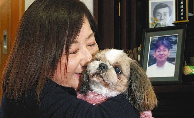 夫清さんの写真を飾った居間で、愛犬ハナを抱きしめる鶴島道子さん＝愛知県知多市で
