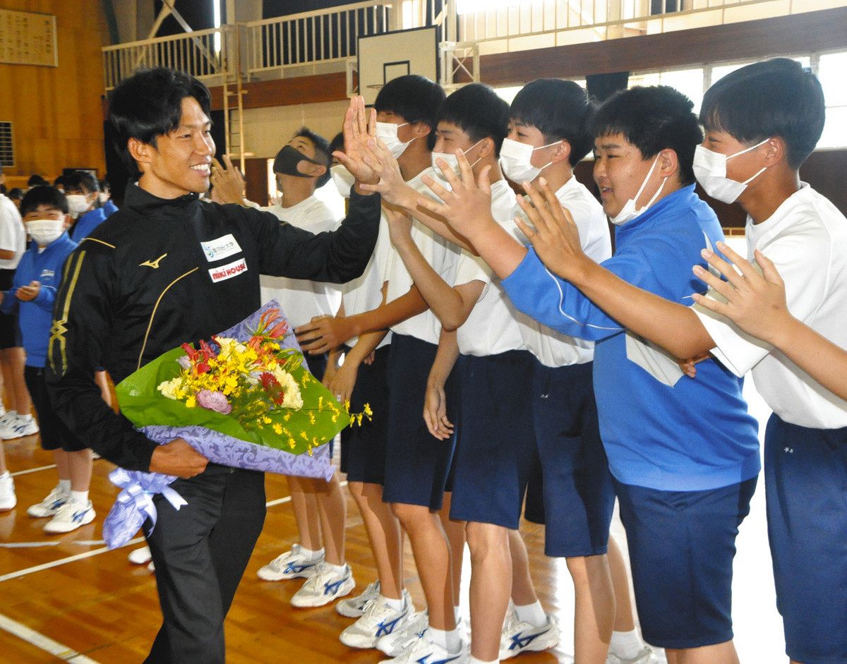 花束を手に後輩たちとハイタッチで活躍を誓う田中選手＝中津川市第一中で