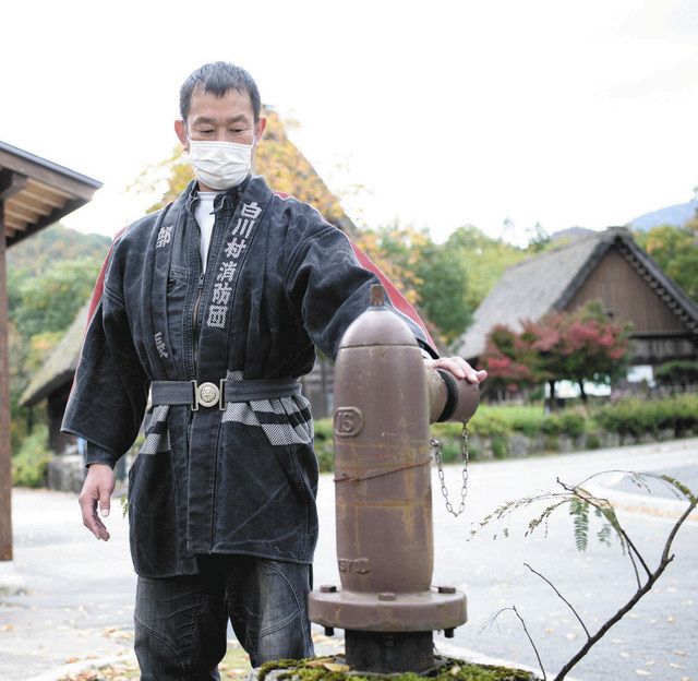 出火当時、初期消火活動に使った消火栓をみつめる黒木さん＝白川村荻町で