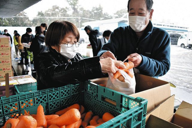 袋いっぱいに訳ありのニンジンなどを詰め込む買い物客＝小浜市川崎の同市総合卸売市場で 