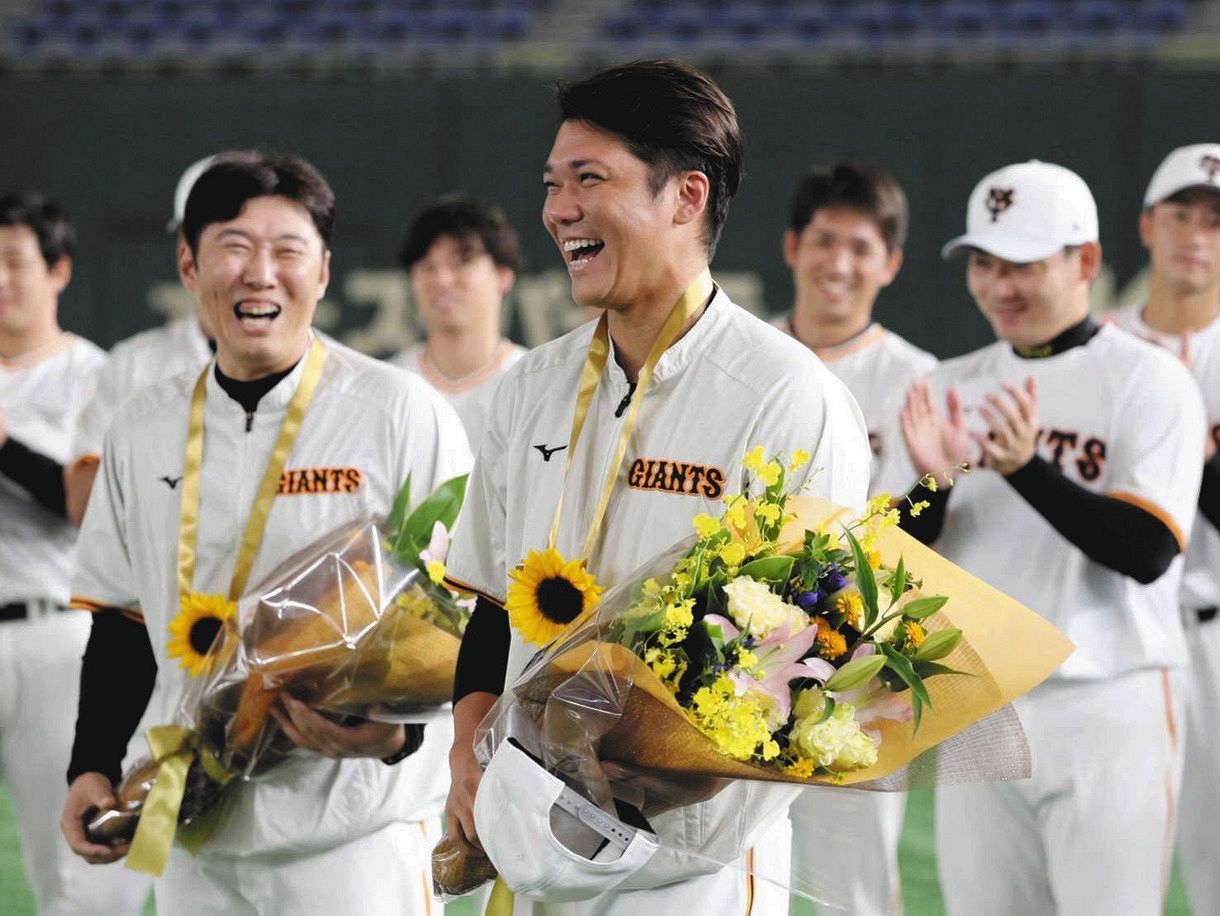 練習開始前にナインから祝福され、笑顔の坂本。左は侍ジャパンでバッテリーコーチを務めた村田ブルペンコーチ＝東京ドームで（読売巨人軍提供）