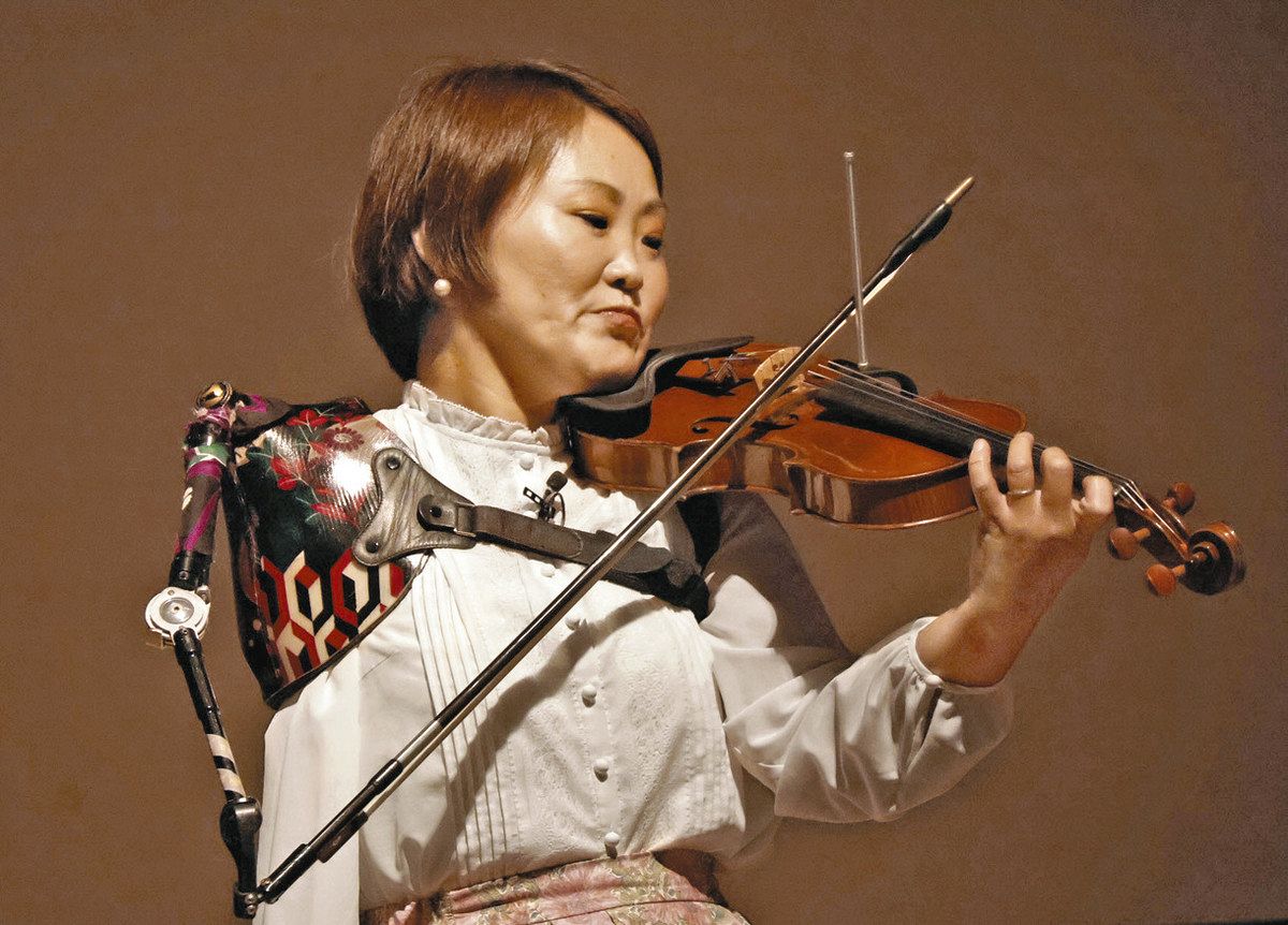 義手を使ってバイオリンを奏でる伊藤さん＝一宮市一宮市民会館で