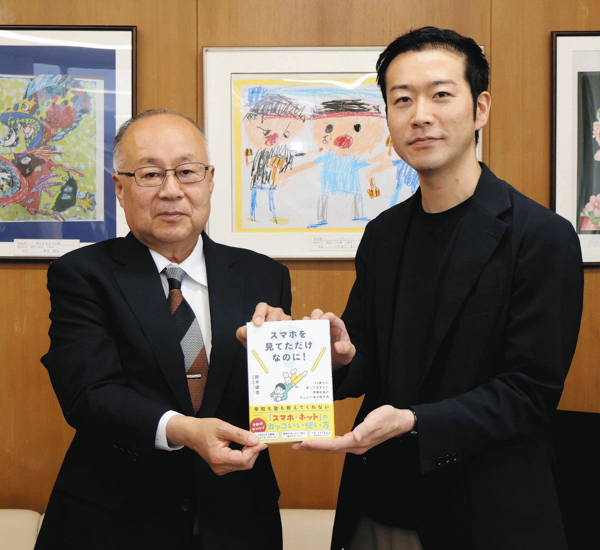 書籍を寄贈した鈴木さん（右）＝瑞浪市役所で