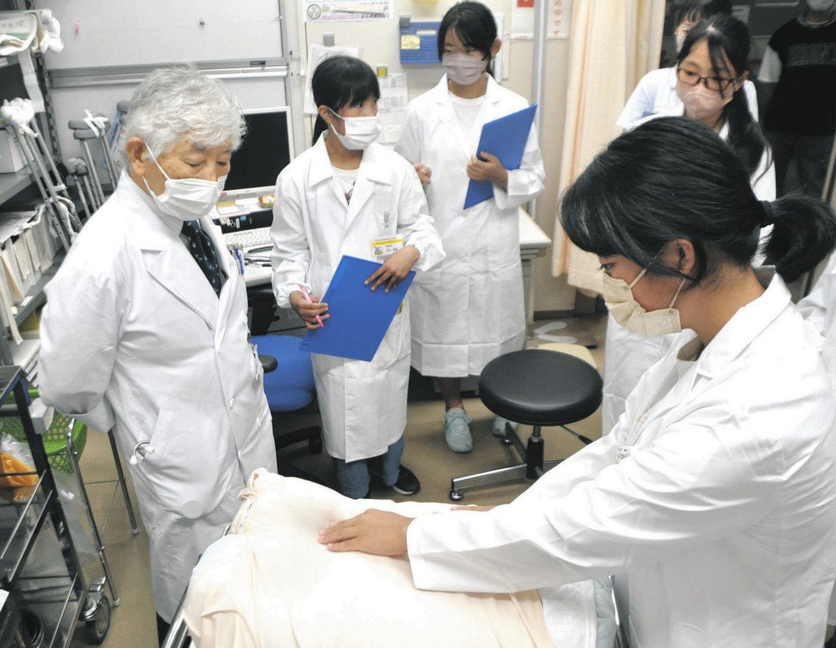 高山所長（左）に診察の初歩を教わる小学生たち＝中津川市の坂下診療所で