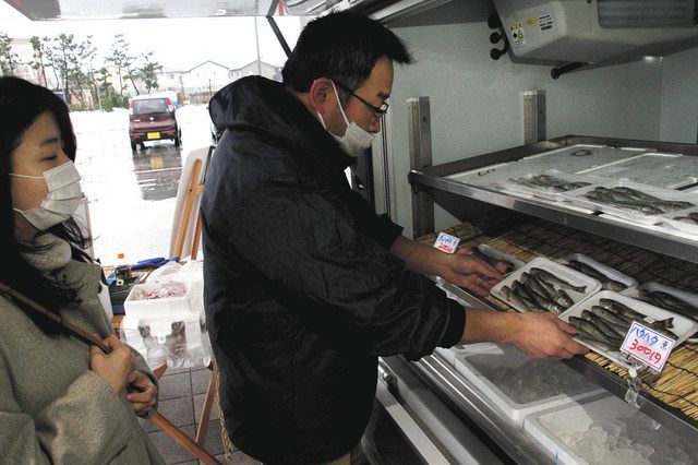 最後の土曜魚市で接客する新屋星治さん（右）＝羽咋市の道の駅のと千里浜で 
