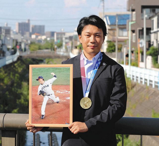 金メダルと準々決勝の米国戦で投げた写真を手に、決意を語った大野雄＝名古屋市内で