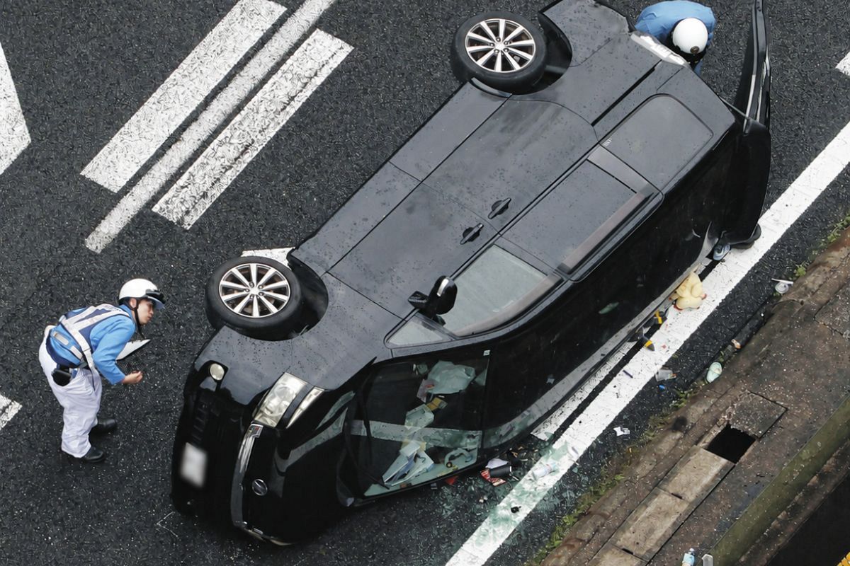 事故で横転した乗用車を調べる警察官＝25日午後、岐阜県瑞浪市で、本社ヘリ「わかづる」から