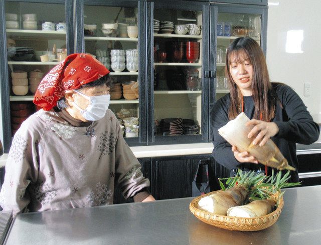 この朝、採れたばかりのタケノコを手に、料理の仕方などを店の人に聞く富山福祉短大の丹羽夏野さん（右）＝高岡市西田で 