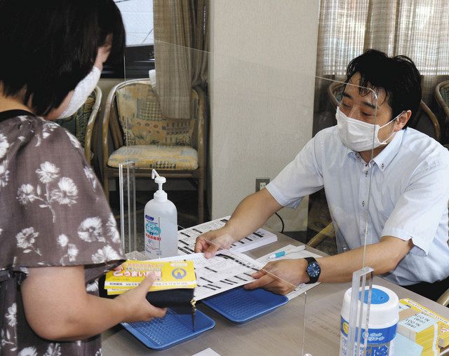 食事券を販売する尾鷲商議所の担当者（右）＝尾鷲市の尾鷲商議所で 