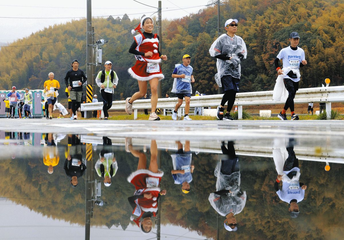 雨でできた水たまりのそばを走るランナーたち＝松阪市阿波曽町で