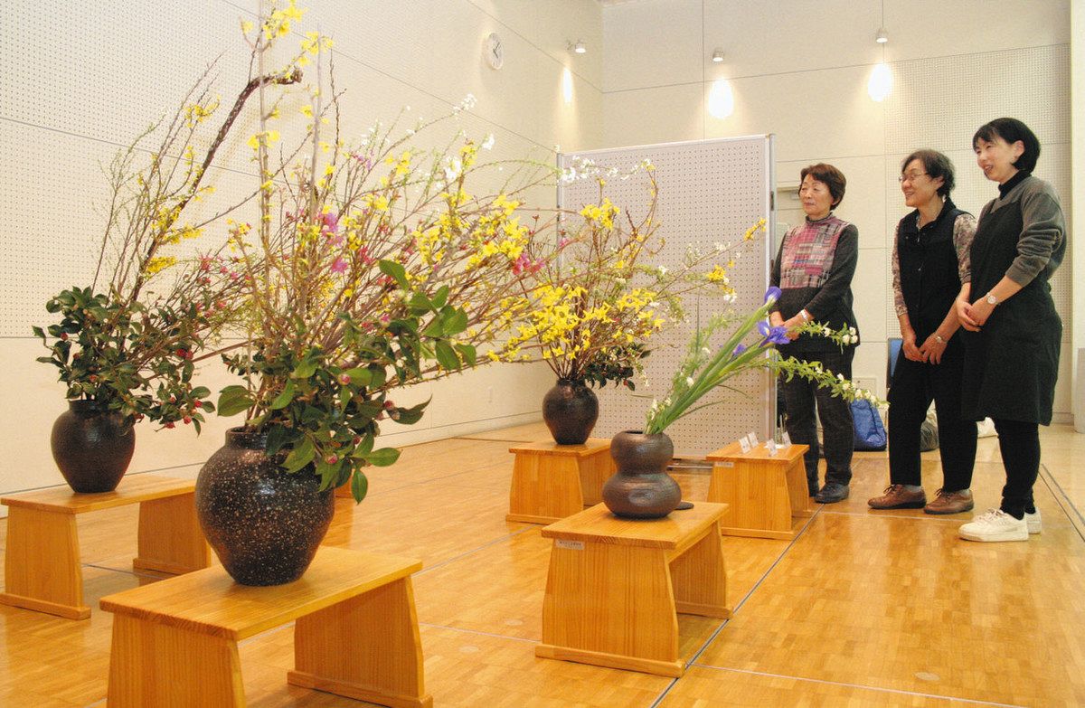 流派を超え、彩りと個性が競演する「いけばな作品」。鈴木会長（左）らが鑑賞を呼びかける＝安曇野市豊科交流学習センター「きぼう」で
