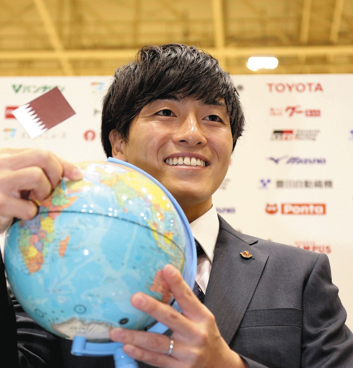サッカーW杯カタール大会の日本代表メンバーに選ばれ、地球儀の中からカタールを示す名古屋・相馬勇紀