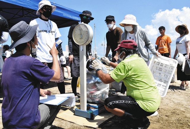 ユーチューバーら参加者が拾ったごみの重さを量るスタッフ＝羽咋市柴垣町で 