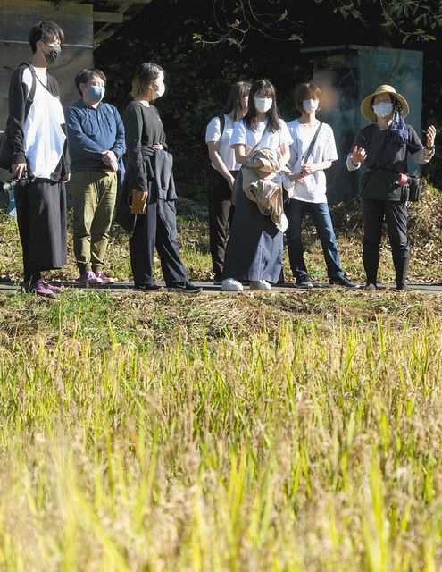 田んぼの前で市川さん（右）の話を聞く学生ら＝辰野町横川で 