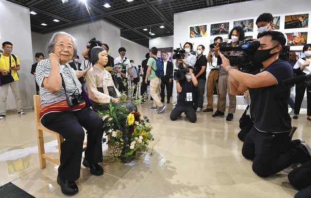 戦時中の慰安婦を象徴する「平和の少女像」の横に座る共同代表の久野綾子さん（左手前）＝６日午前、名古屋・栄の市民ギャラリー栄で