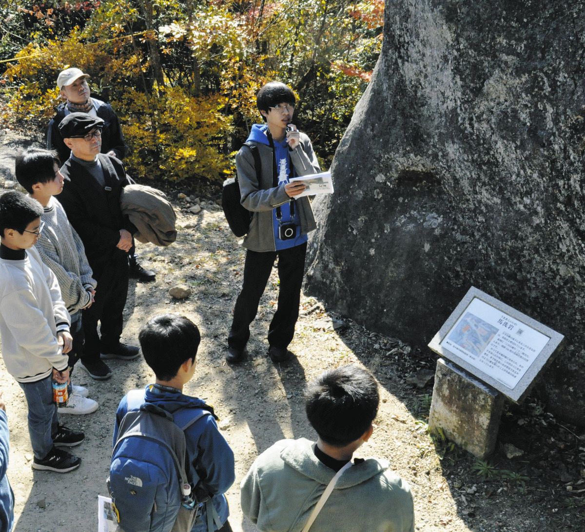 巨岩にまつわる伝説を解説する栗原さん（中央）＝中津川市の苗木城跡で