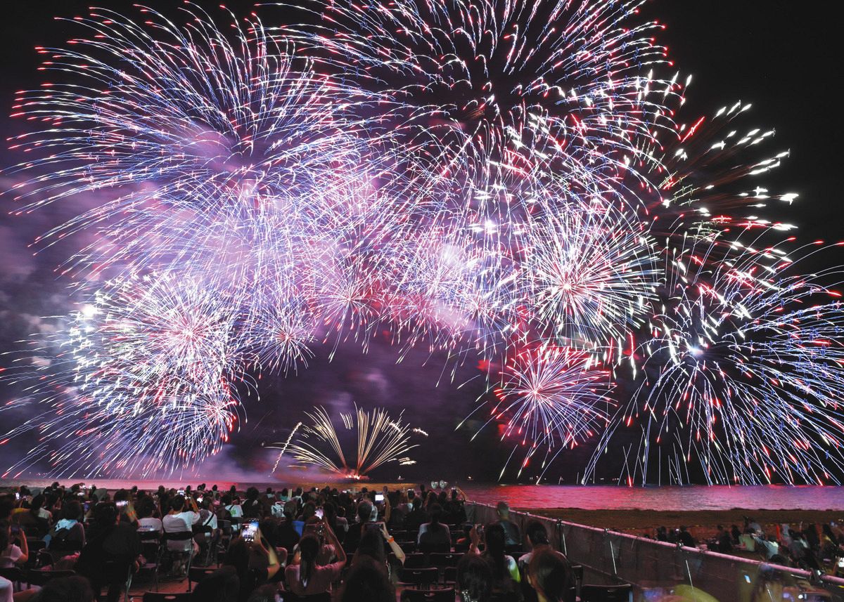 海上から打ち上げられ上空を彩る花火＝津市（比較明合成）で
