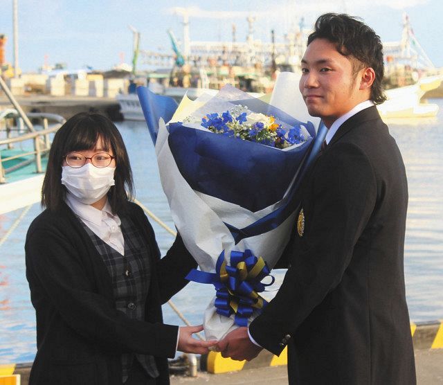漁協関係者から祝福の花束を受け取る日本ハムからドラフト１位指名された苫小牧駒大・伊藤大海投手（右）