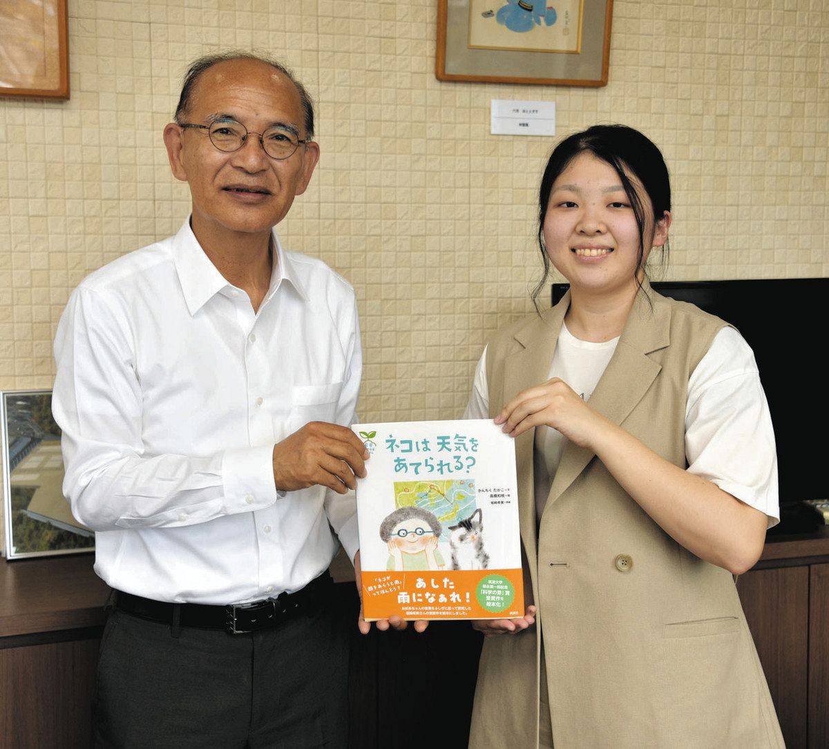仙石教育長（左）に絵本を手渡す坂崎さん＝多治見市役所駅北庁舎で
