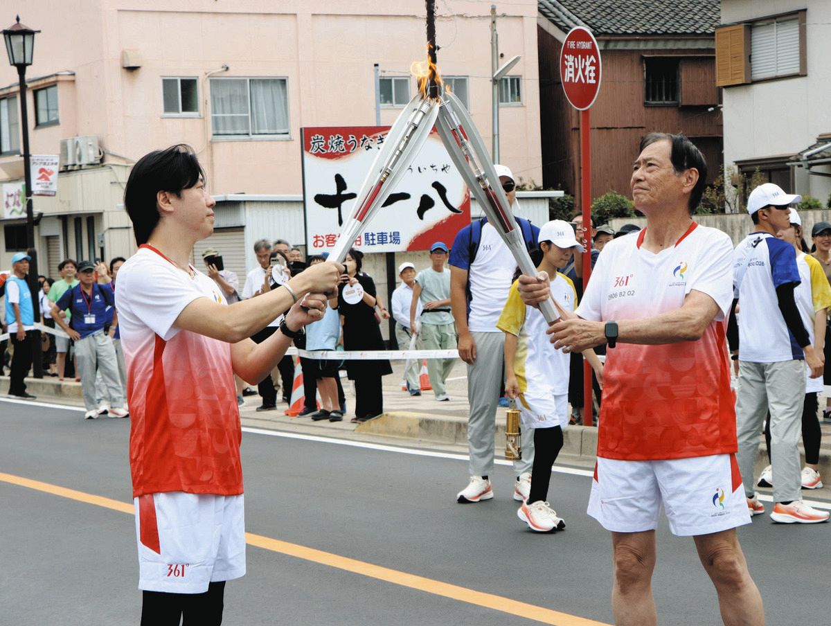 前の走者から聖火を引き継ぐ板倉さん（右）＝碧南市で