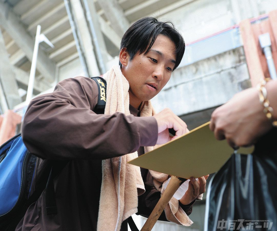 練習後、訪れたファンにサインする田中
