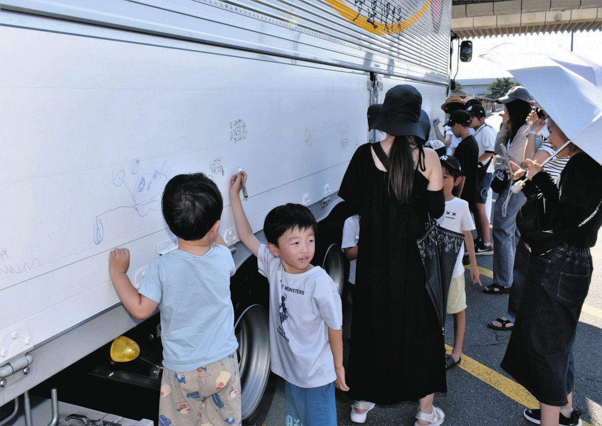 トラックのコンテナに願い事や絵をかく子どもら＝津市のボートレース津で
